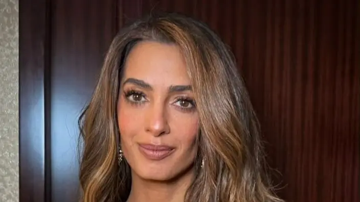 Amal Clooney posando nos Albies 2026 com vestido dourado
